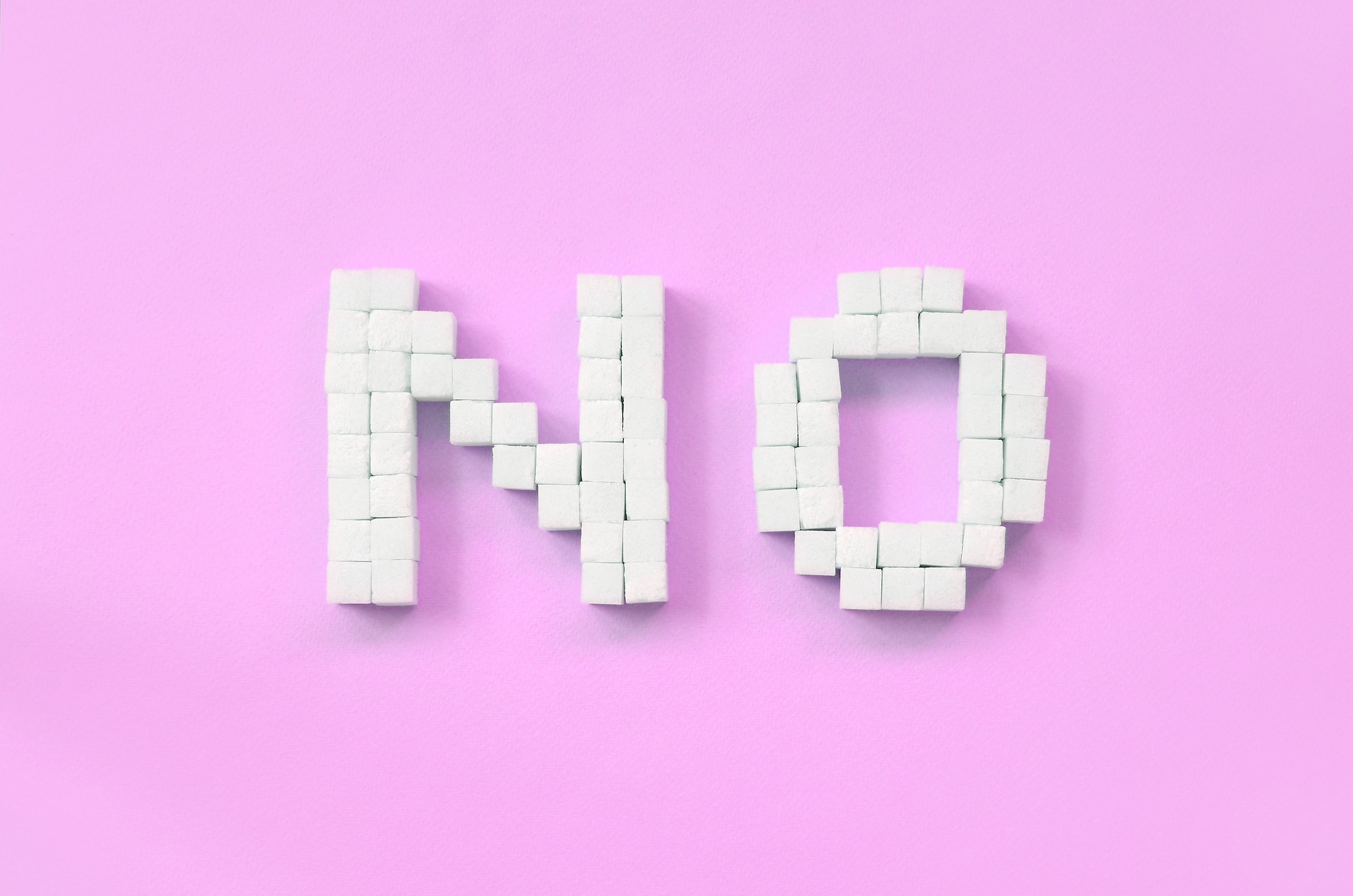NO Letters of sugar cubes on a pastel pink background
